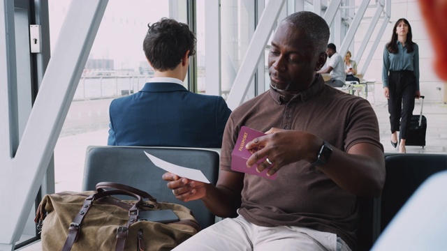 在起飞前，一个商人坐在机场的候机室里，拿着行李检查旅行文件视频素材
