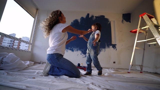 母亲和儿子在家里装修期间玩油漆，玩得很开心，笑着画着他们的脸视频下载
