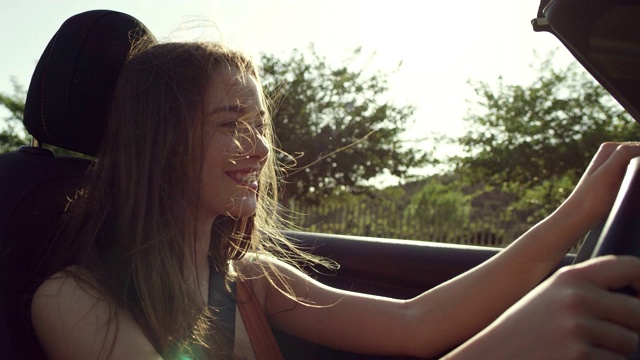 年轻女子坐在敞篷车里，头发在风中飘动视频素材