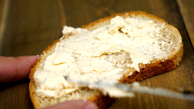 男人做了个花生酱三明治…男性的手在厨房的面包上涂黄油的特写视频素材
