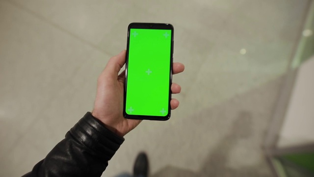 第一人称视角，男性手持绿色屏幕的智能手机走在商场视频素材