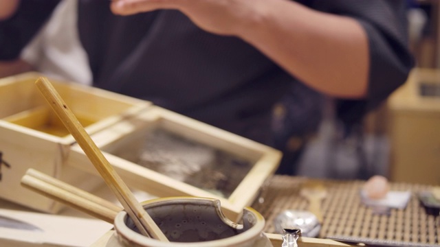 日式omagase餐厅的厨师用筷子烹饪，并把烧鱼酱海胆放在日式料理中。视频素材