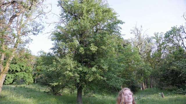 漂亮女人走过森林，欣赏树木。美丽的女孩在户外享受大自然。视频素材