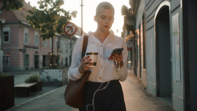 在人行道上一边喝咖啡一边玩智能手机的女士视频素材