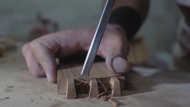 特写镜头，一个木工在一个工作台上用凿子在木头上做一个燕尾。木匠在加工橡木坯。4 k。4 k的视频。缓慢的运动。24帧/秒视频素材