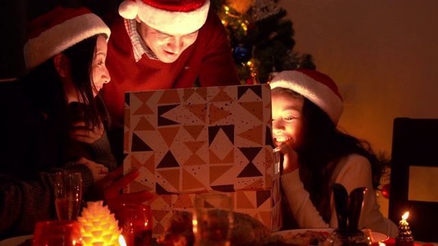 在圣诞节那天，这个幸福的家庭有了爸爸和妈妈。爸爸和妈妈送了一个奇妙的礼盒，盒子在明亮的灯光下打开。视频素材