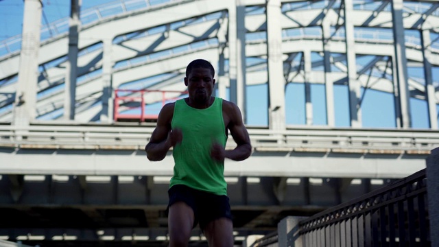 年轻的非洲运动员在城市桥上练习倒跑练习时积极地呼吸视频下载