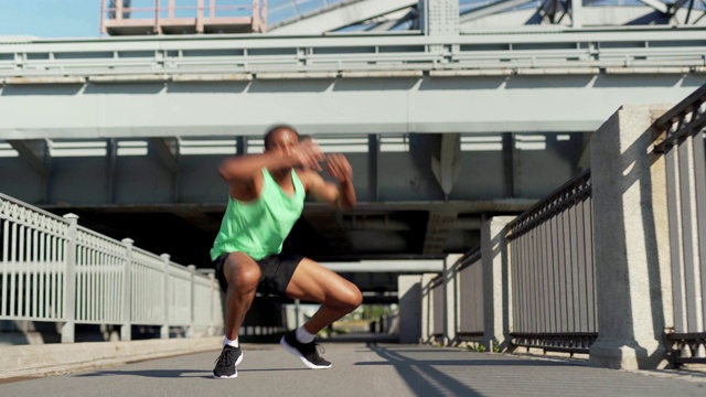 多利拍摄的坚定的年轻非洲运动员在城市大桥上练习鸭子走路视频下载