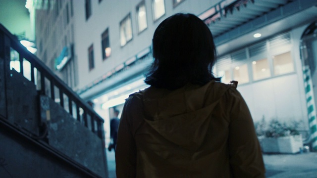 在日本东京，一名年轻女子戴着耳机走在夜里视频素材