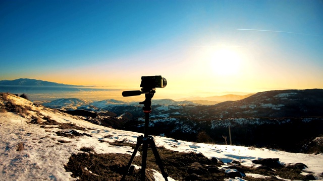 三脚架上的无反光镜单反相机拍摄山区冬季日落的延时视频素材