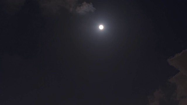 《满月在夜空中穿过乌云》4k镜头，延时拍摄。神秘的月亮在云中从闪耀到完全被乌云覆盖。月光在漆黑的夜空中闪耀。视频素材