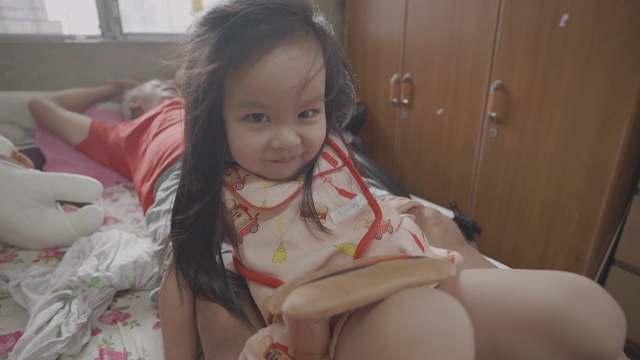慢动作亚洲小女孩与爷爷在床上玩耍。视频素材