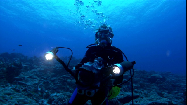 潜水员在水下拿着一个大相机。视频下载