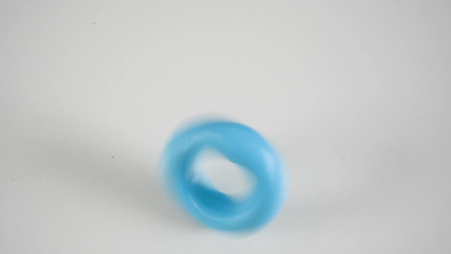 一个浅蓝色的塑料环在一张白色的桌子上旋转视频素材