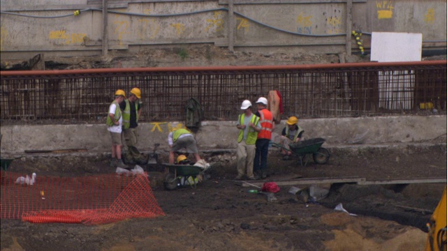 建筑工人在挖掘工地操作挖土机。视频素材