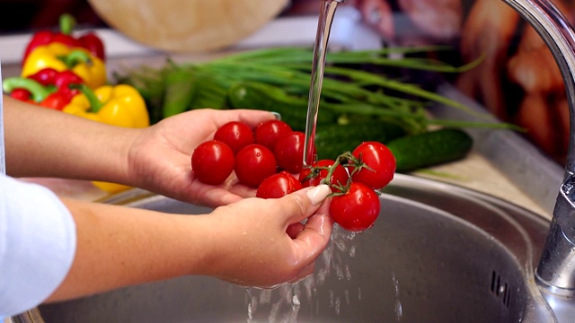 一个女人在厨房水槽下洗樱桃番茄的特写镜头。视频素材