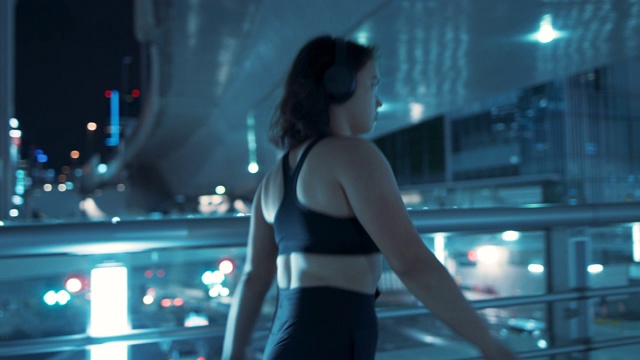 在日本东京，年轻女子穿着紧身裤和运动胸罩在晚上走路视频素材