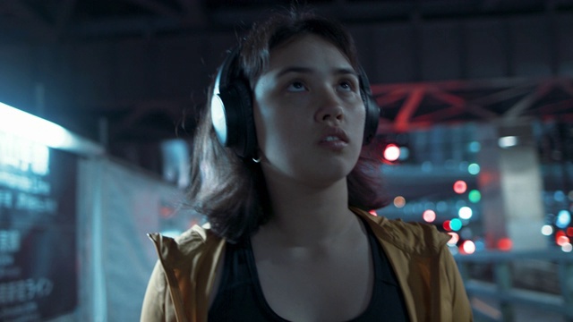 在日本东京的夜晚，戴着耳机走路的年轻女子视频下载