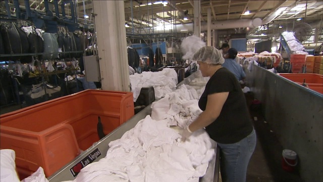 洗衣工人在传送带上整理床单。视频下载