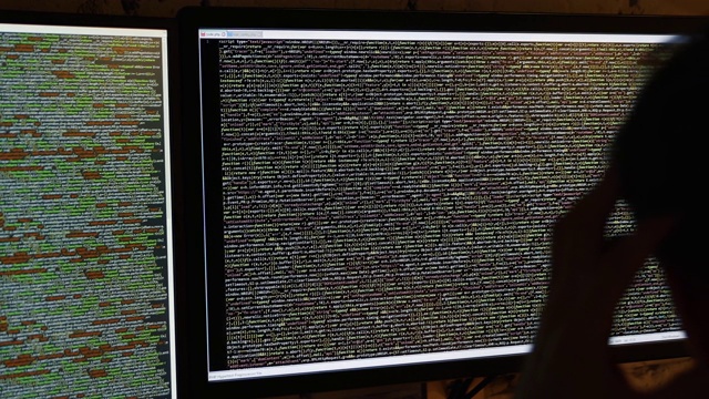 程序员在暗室工作。在电脑屏幕上滚动代码视频素材