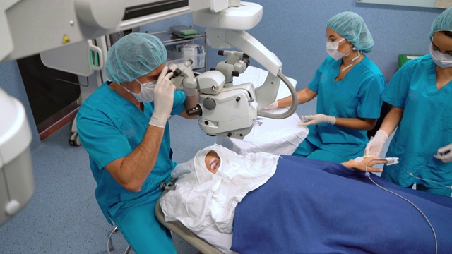外科医生在准备显微镜进行眼科手术，而外科医生在准备其他器械视频素材