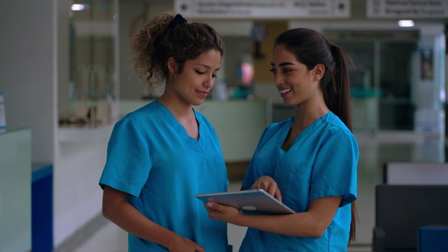 在医院工作的护士使用数字平板电脑说话和微笑视频素材