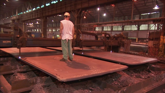 一个建筑工人从两块钢板上走过，机器从上面经过。视频下载