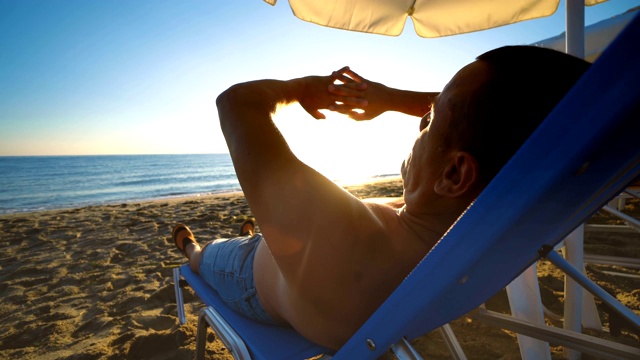 夕阳西下，男人们躺在沙滩上玩着太阳。精神，幸福，正能量，放松的概念视频下载
