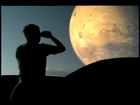 一个人用双筒望远镜望着山顶上巨大的月亮。视频下载