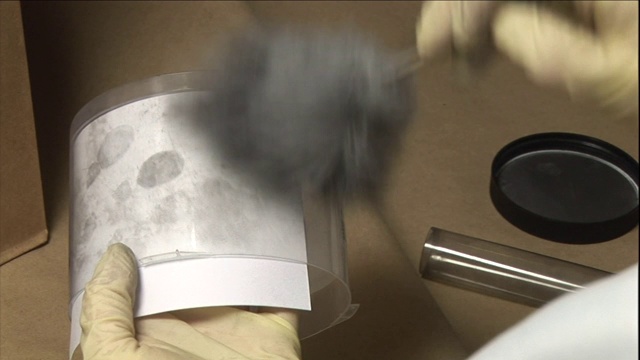 一名技术人员掸去CD轴盖上的灰尘，以便打印。视频素材