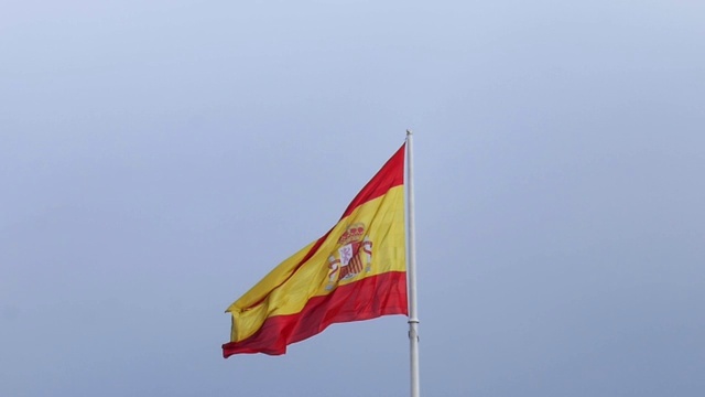 西班牙国旗上的一杆慢镜头刮风的日子蔚蓝的天空视频素材