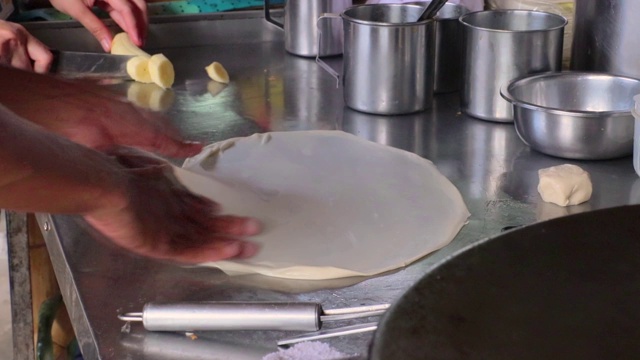 烤饼制作，通过烤饼机将面粉和油脱粒。印度传统街头小吃。泰国煎饼、香蕉和鸡蛋。泰国街头小吃和甜点。制作烤肉点心视频素材