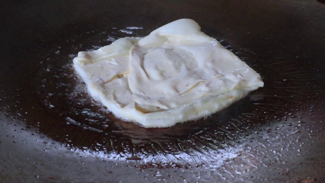 烤饼制作，通过烤饼机将面粉和油脱粒。印度传统街头小吃。泰国煎饼、香蕉和鸡蛋。泰国街头小吃和甜点。制作烤肉点心视频素材