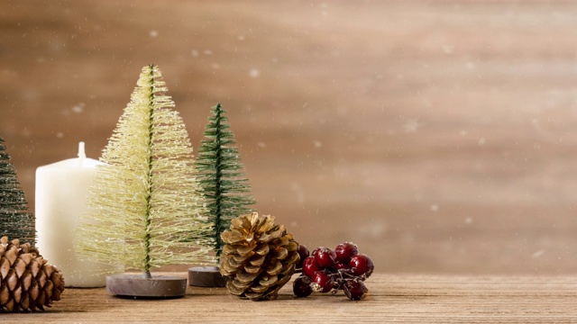 圣诞快乐和新年快乐的背景与圣诞树和槲寄生叶和松果在木桌子上与雪花。寒假季节贺卡视频素材