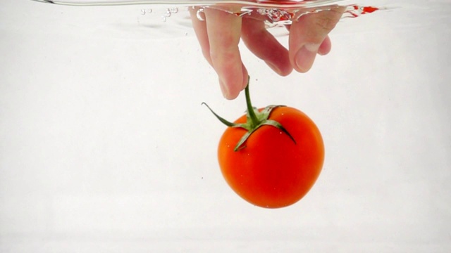 白色背景中央，一名男子试图抓住水中的番茄视频下载