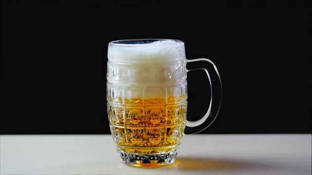 啤酒倒进白色背景的玻璃杯里。慢动作视频下载