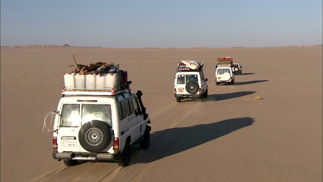 载满货物的suv开着大篷车穿越贫瘠的沙漠。视频下载