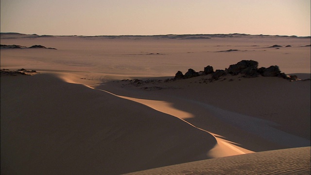 沙丘和岩层耸立在撒哈拉沙漠的Gilf Kebir地区。视频下载