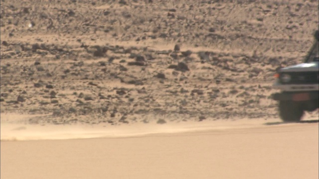越野车在Gilf Kebir上行驶时尘土飞扬。视频下载