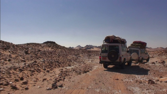 一队suv车队行驶在Gilf Kebir崎岖不平的土路上。视频下载
