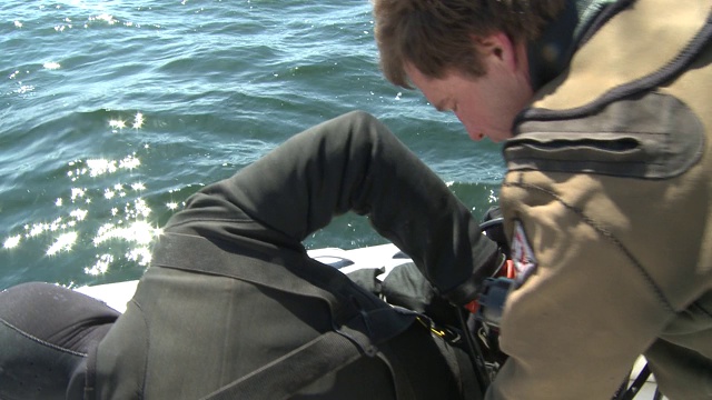 船上的一个人帮助潜水员做准备工作。视频下载