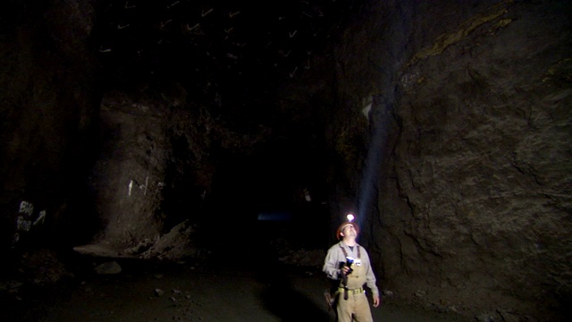 一名矿工用手电筒检查矿井内部。视频素材