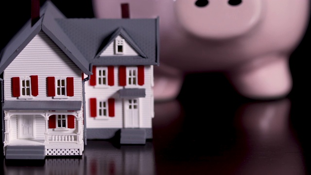 小猪储钱罐和暗木表面的微型房子视频素材