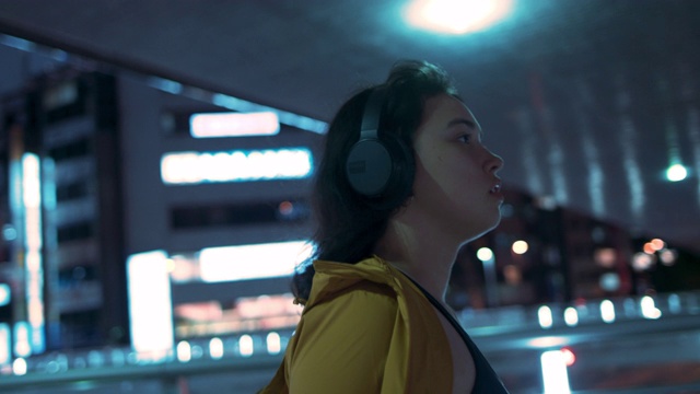 日本东京，一名年轻女子戴着耳机在桥下行走视频素材