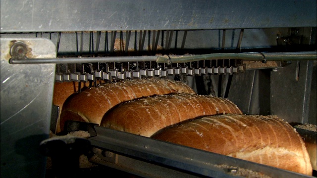面包从面包工厂的自动切片机下经过。视频下载
