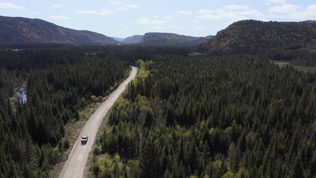 视频，鸟瞰图上的车辆通过美丽多彩的秋天森林在阳光明媚的秋天，加拿大魁北克视频素材