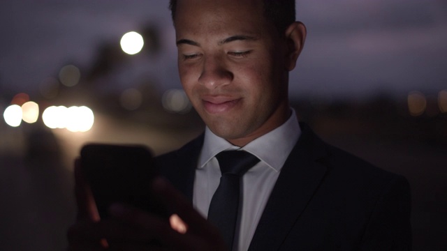 加州大学年轻的商人晚上用手机发短信视频素材