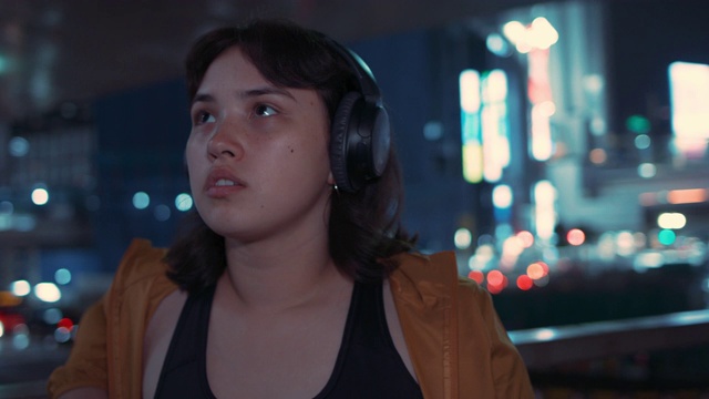 日本东京晚上戴着耳机的年轻女子的肖像视频素材
