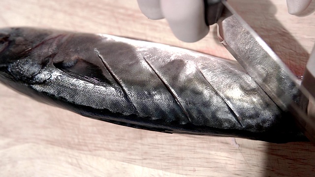 慢镜头剪辑，厨师正在用刀切鱼肉烹饪。视频素材