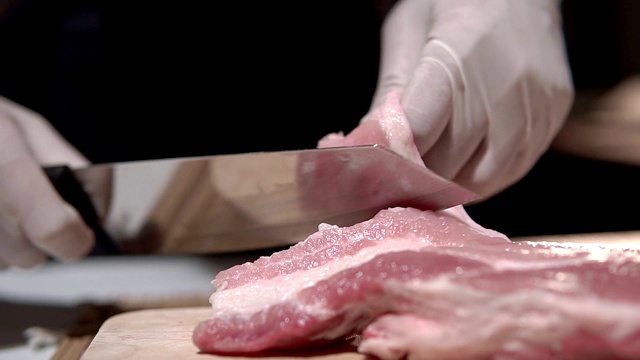 慢镜头剪辑，厨师正在用刀切猪肉。视频素材